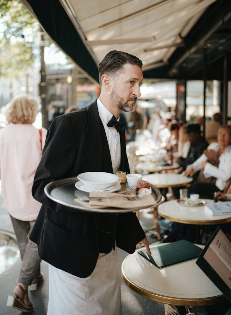 A man in a tuxedo carrying a tray of food